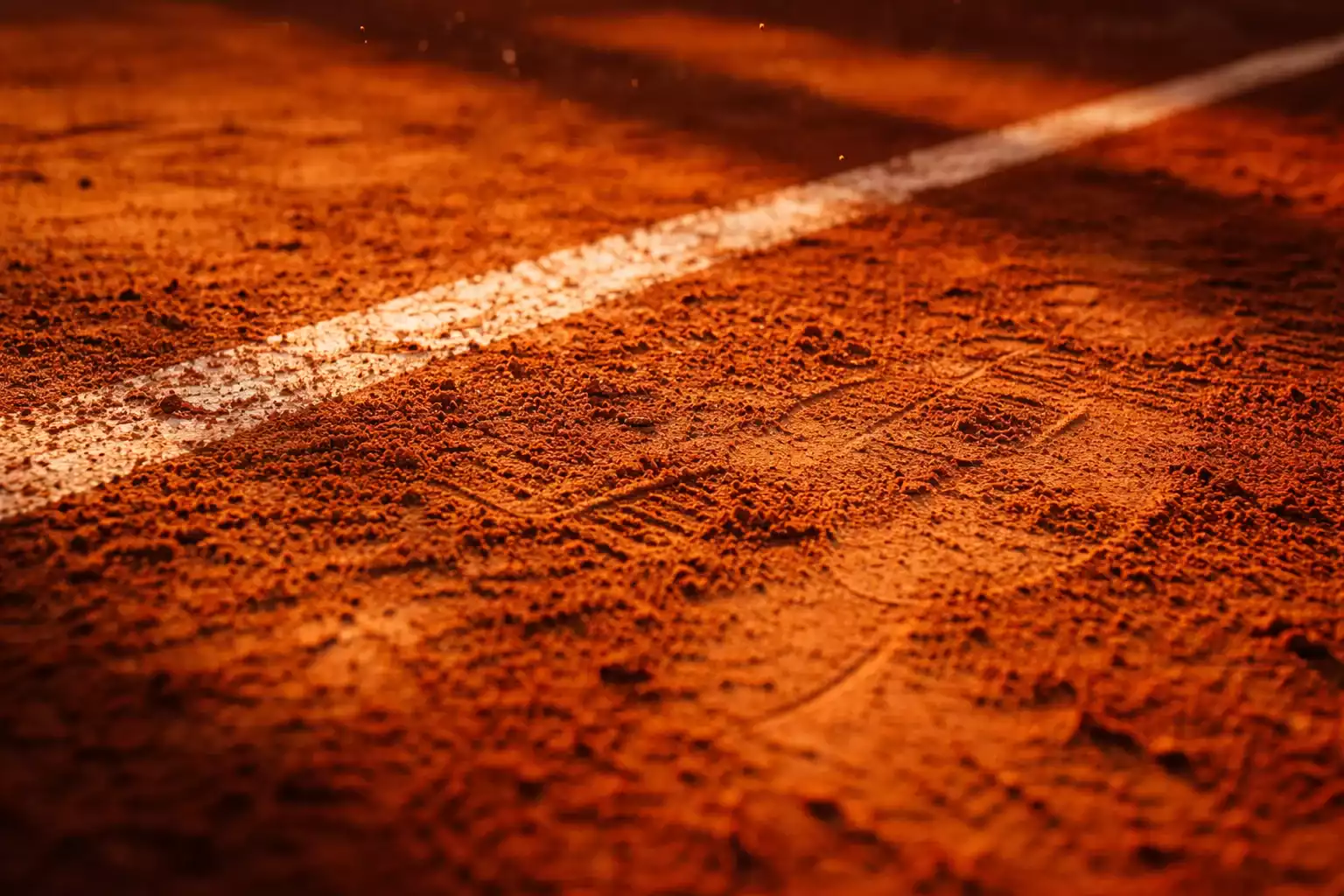 Nahaufnahme der roten Sandplatzoberflaeche bei Roland Garros mit sichtbaren Fussabdruecken